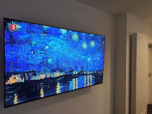 Ein Flachbildfernseher an der Wand, der ein Gemälde zeigt.