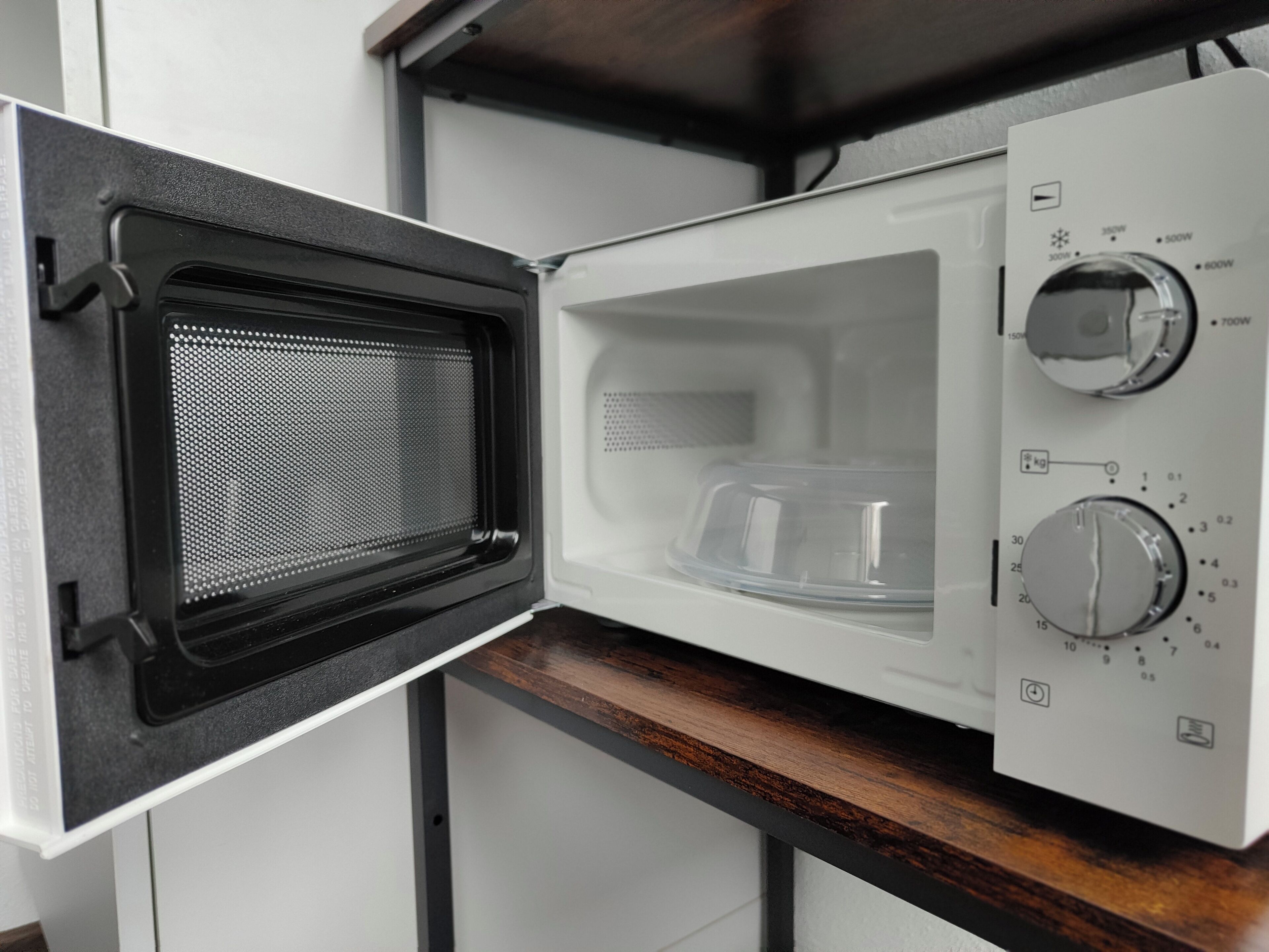 An open microwave with a digital display, a power button, and a timer.