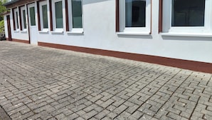 Um edifício com fachada branca, várias janelas e um chão de tijolos.