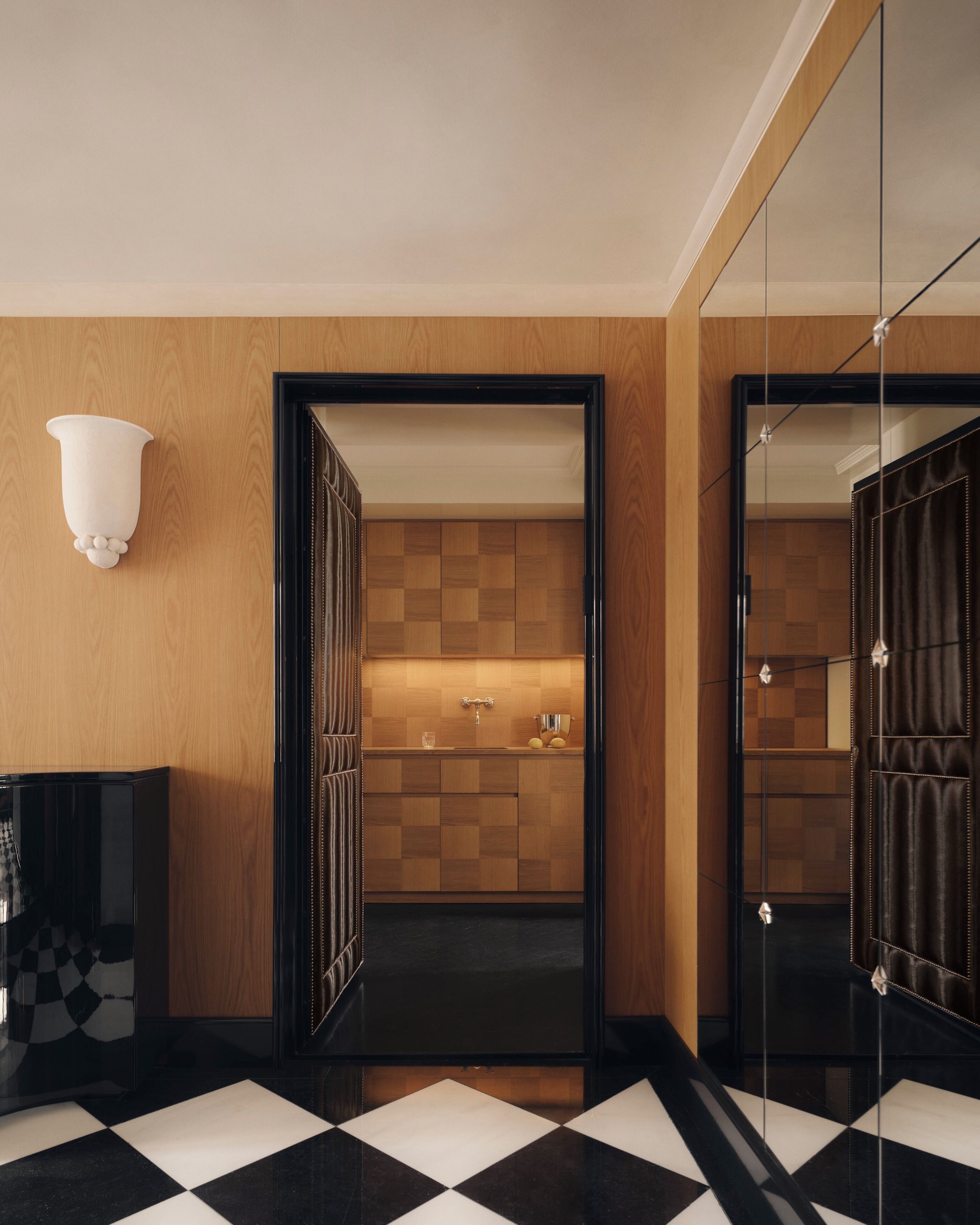 Une salle de bain moderne avec un carrelage à motifs géométriques, des meubles en bois, un miroir et un luminaire.