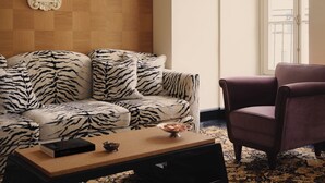 En stue med en sofa i zebra-mønster, en trævæg, et spejl, et sofabord og en lilla lænestol.
