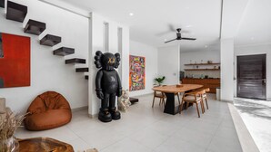 A modern interior with a dining area, a large abstract painting, and a unique black sculpture. - L'Angelo Villa Canggu (Canggu)