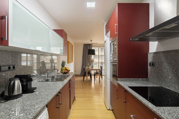 A modern kitchen with granite countertops, stainless steel appliances, and a dining area with a table and chairs.