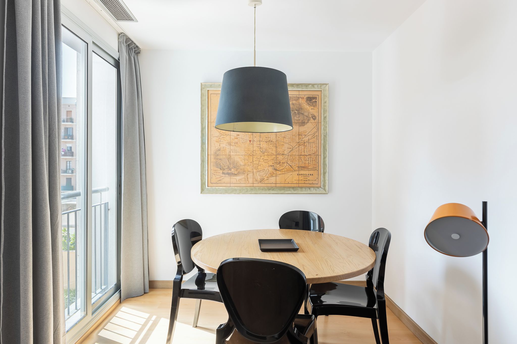 Un comedor con una mesa redonda, cuatro sillas, un mapa en la pared y una lámpara colgante.