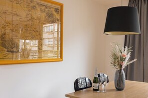 A dining table with a map, a bottle of wine, and a vase with flowers.