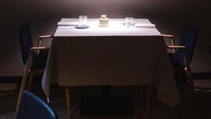 A dining area with a table set for two, chairs, a framed picture on the wall, and a small table lamp. - Stilla Rooms and Contemporary Cuisine (Colognola ai Colli)