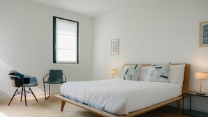 A bedroom with a bed, two chairs, a window, and a bedside table. - Stilla Rooms and Contemporary Cuisine (Colognola ai Colli)