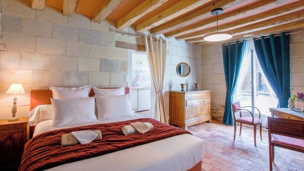 A bedroom with a bed, wooden headboard, a dresser, a chair, and a window with curtains.