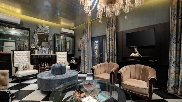 A luxurious living room with a chandelier, a television, and classic furniture.