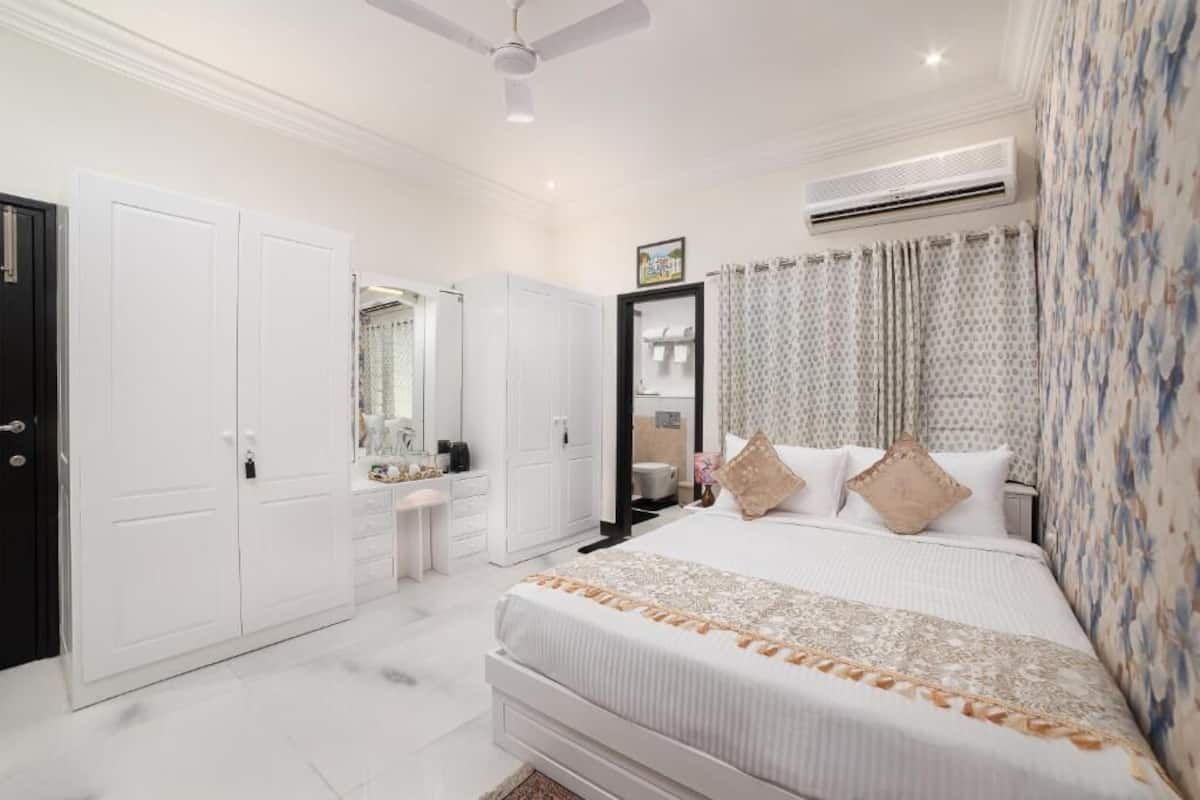 Un dormitorio con cama, armario, tocador y aire acondicionado.
