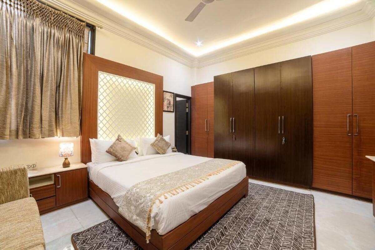 Un dormitorio con una cama grande, un armario de madera y una mesita de noche con lámpara.