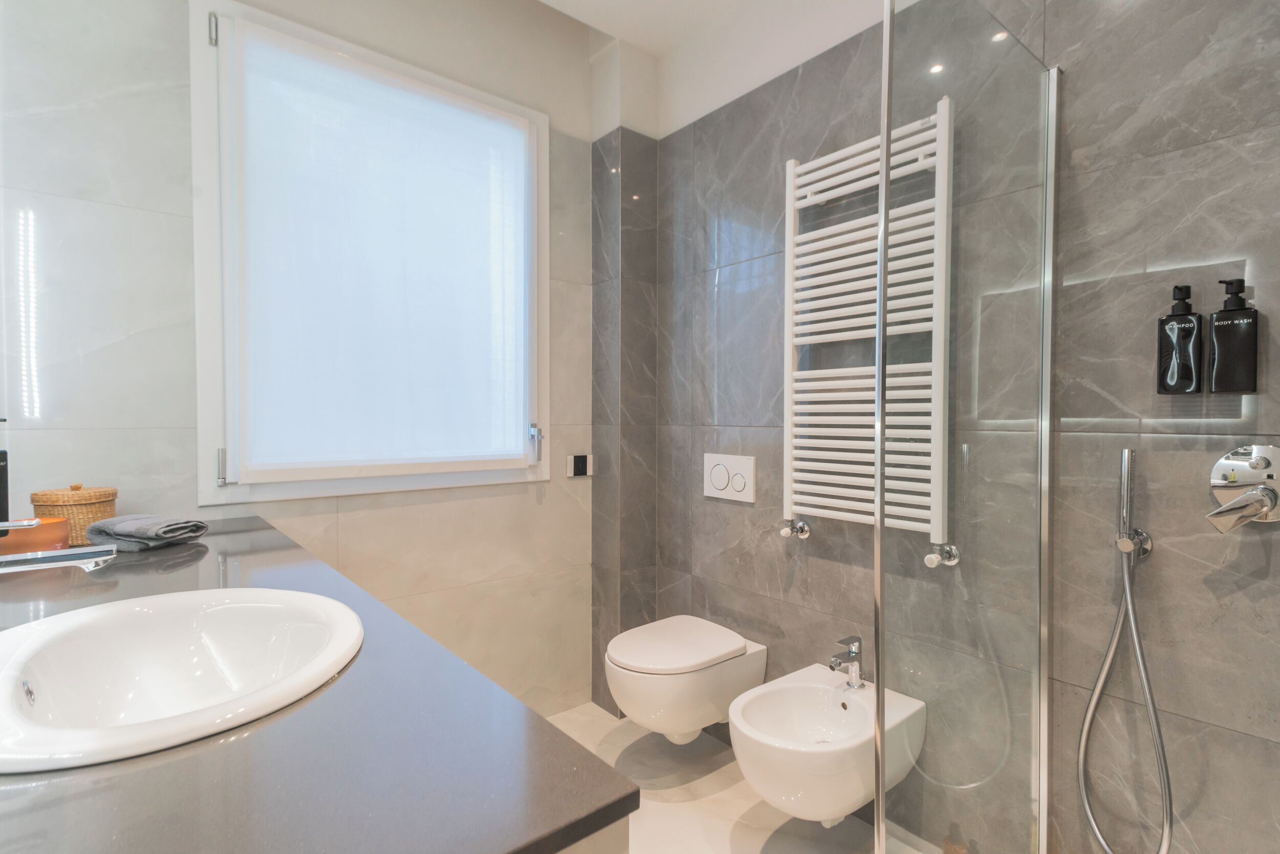 Une salle de bain moderne dotée d’un grand lavabo, de toilettes, d’un bidet et d’une douche à parois de verre.