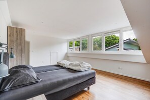 Ett modernt sovrum med ett fönster i loftstil, en säng, ett skrivbord och en lampa.