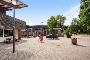 Een buitenplaats met een picknicktafel, een bank, een lantaarnpaal en een vuilnisbak.