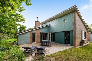 Ett tvåvåningshus med en uteplats, ett garage och en täckt sittplats utomhus.