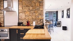 A modern kitchen with a stone wall, a stainless steel range hood, and a wooden countertop. - Art Loft # Design - Near Croisette | Beaches - A/C (Cannes)
