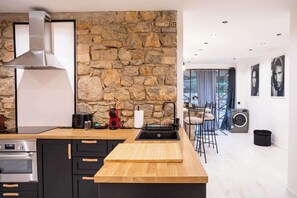 Eine moderne Küche mit Steinwand, Edelstahl-Dunstabzugshaube und Holzarbeitsplatte.