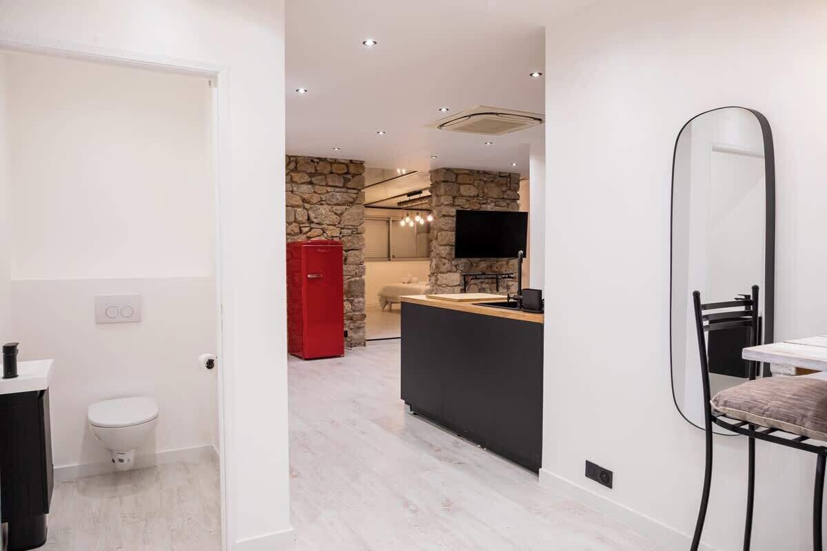 Una cocina moderna con una pared de acento de piedra, un refrigerador rojo y un televisor de pantalla plana.