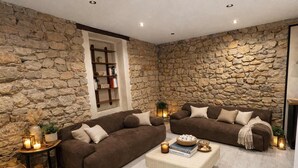 A cozy living room with stone walls, two brown sofas, a beige ottoman, and a bookshelf. - Art Loft # Design - Near Croisette | Beaches - A/C (Cannes)
