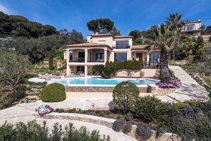 Eine Villa im mediterranen Stil mit Swimmingpool, mehreren Balkonen und üppiger Bepflanzung.