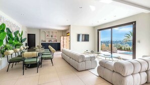 A spacious living area with a dining set, a large sofa, and a view of the outdoors. - Villa Picasso # Panoramic View - Luxury - Jacuzzi (Vallauris)