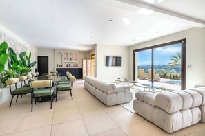 Ein großzügiger Wohnbereich mit Esstisch, einer großen Couch und Blick ins Freie.