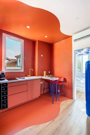 Eine moderne Küche mit gewölbter Decke, einem Fenster mit Blick auf ein Gebäude und einem blauen Trainingsger ät in der Ecke.