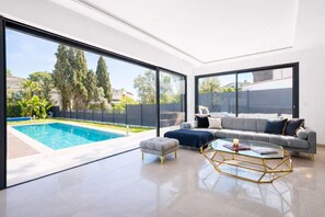 A modern living room with a pool, large windows, and a grey sofa. - Villa Bella Vista # Pool - Luxury & Serenity (Le Cannet)
