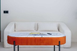 A room with a white sofa, a small round table with a white marble top, and a red upholstered stool. - The Tropezian Garden # Luxury - Near Sea - Terace (Saint-Tropez)