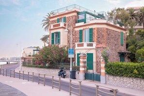 A stone building with green shutters, a paved walkway, and a view of the sea. - Love Nest # Sea View - Close to Beach and Port (Cannes)