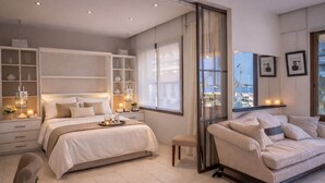 Un dormitorio moderno con una cama grande, mesitas de noche, un sofá y vistas a la ciudad.