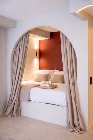 Un dormitorio con cama, cortinas y una lámpara fijada a la pared.