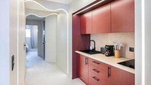 A modern kitchen with a curved countertop, a built-in stove, and a red cabinet. - Architect Suite # Chic Design - Croisette - Beach (Cannes)