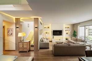 A modern living room with a staircase, a flat-screen TV, and a sofa. - Breeze @ Lakeview Res I Nesty Hospitality (New Cairo City)