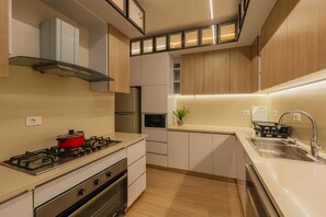 A modern kitchen with a gas stove, oven, microwave, and a sink with a stainless steel faucet. - Breeze @ Lakeview Res I Nesty Hospitality (New Cairo City)