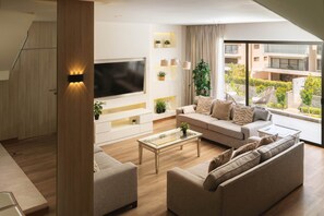 A modern living room with a large flat-screen TV, a sofa, a coffee table, and a view of a building through large windows. - Breeze @ Lakeview Res I Nesty Hospitality (New Cairo City)