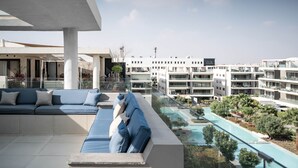 Une terrasse sur le toit avec une piscine, un espace de détente et des bâtiments modernes en arrière-plan.