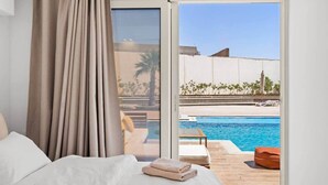 Un dormitorio con una cama grande, vistas a una piscina y un balcón.