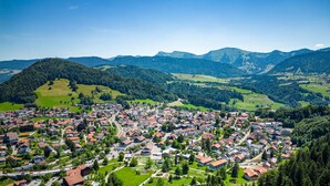 A town with a prominent church, surrounded by green hills and mountains. - "AllgäuLiebe", Oberstaufen (Oberstaufen)