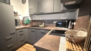 A modern kitchen with grey cabinets, a wooden countertop, a built-in stove, and a microwave. - "AllgäuLiebe", Oberstaufen (Oberstaufen)