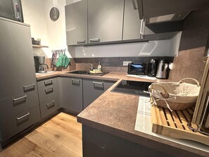 A modern kitchen with grey cabinets, a wooden countertop, a built-in stove, and a microwave. - "AllgäuLiebe", Oberstaufen (Oberstaufen)