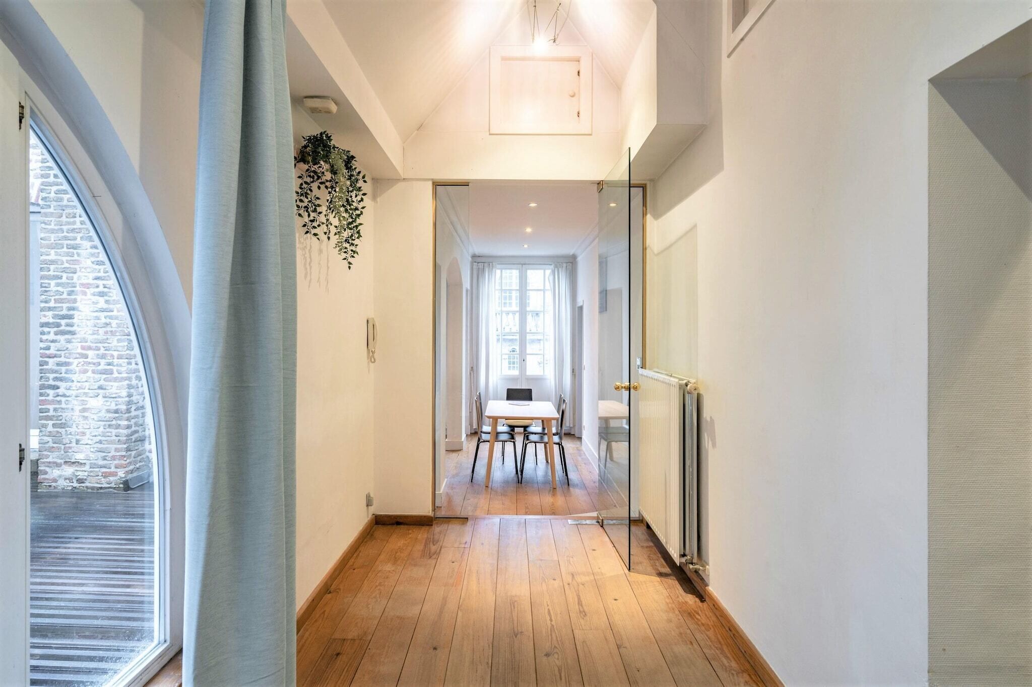 A hallway with a wooden floor, a table with chairs, and a radiator.