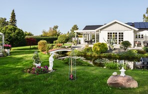 Una casa amb jardí, un estany i panells solars.