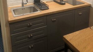 Une cuisine équipée d’un évier en acier inoxydable, d’une machine à café, d’un plateau noir et d’armoires en bois.