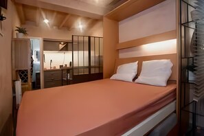A bedroom with a bed, bedside tables, a mirror, and a view of the kitchen. - Studio “Sublime Central Location” with Wi-Fi (Aix-en-Provence)
