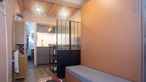 Une pièce de taille modeste comprenant un lit, une petite table, un placard et un coin cuisine.