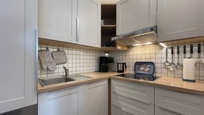 A modern kitchen with white cabinets, a stainless steel sink, and a range hood.