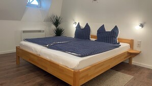 A bedroom with a wooden bed, a skylight, a wall-mounted ship's wheel, and a potted plant.