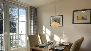 A dining area with a table set for two, a window with curtains, and a pendant light.