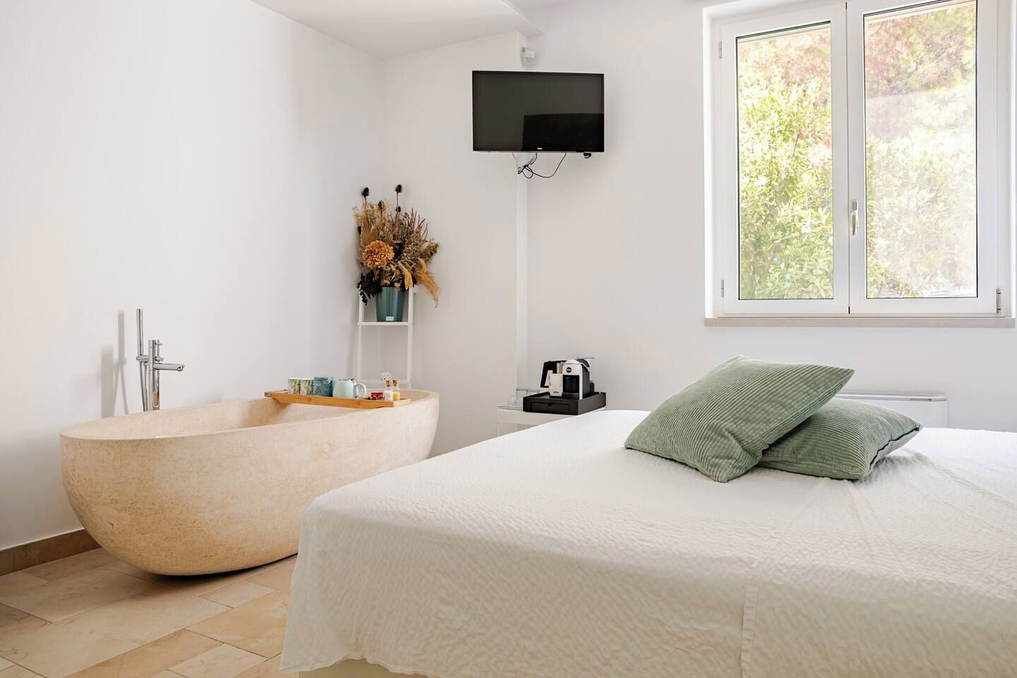 A modern bathroom with a freestanding bathtub, a shower, and a mounted TV.